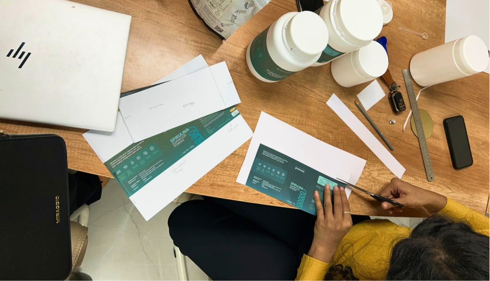 Spirulina powder packaging design being reviewed on a desk