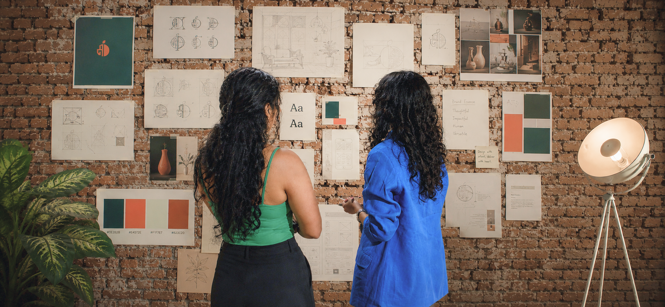 Two designers reviewing a moodboard wall of brand references